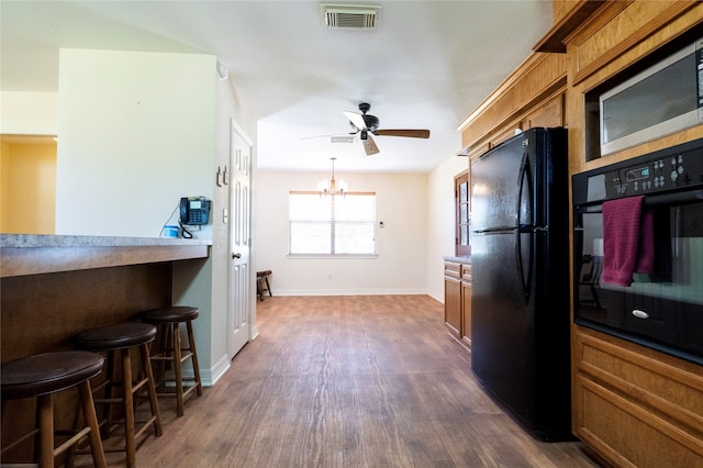 kitchen featuring a breakfast bar, dark hardwood / wood-style floors, black appliances, and ceiling fan with notable chandelier