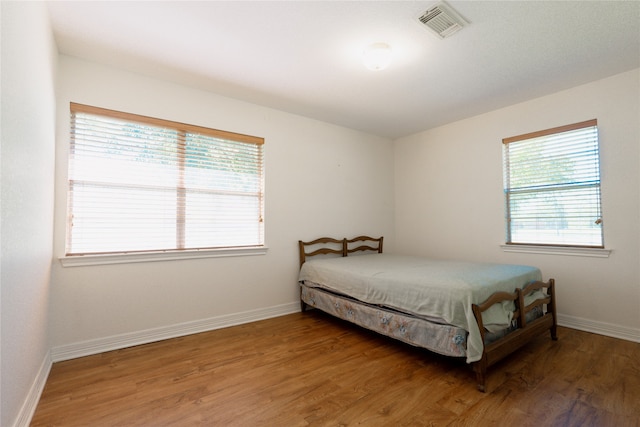 bedroom with multiple windows and hardwood / wood-style flooring