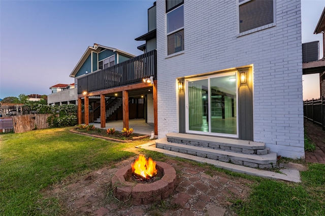 back house at dusk featuring a yard, a fire pit, and a patio area