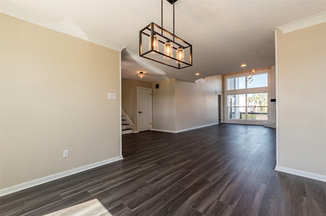 empty room featuring ornamental molding, an inviting chandelier, and dark hardwood / wood-style flooring