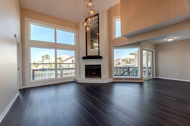 unfurnished living room featuring a fireplace, a towering ceiling, and dark hardwood / wood-style flooring