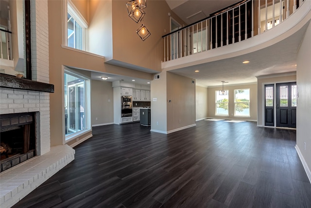 unfurnished living room with a towering ceiling, dark hardwood / wood-style floors, and a fireplace