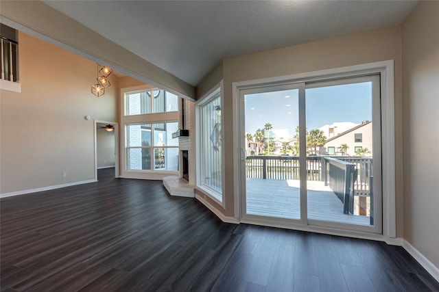 entryway with ceiling fan, a textured ceiling, dark wood-type flooring, a fireplace, and vaulted ceiling