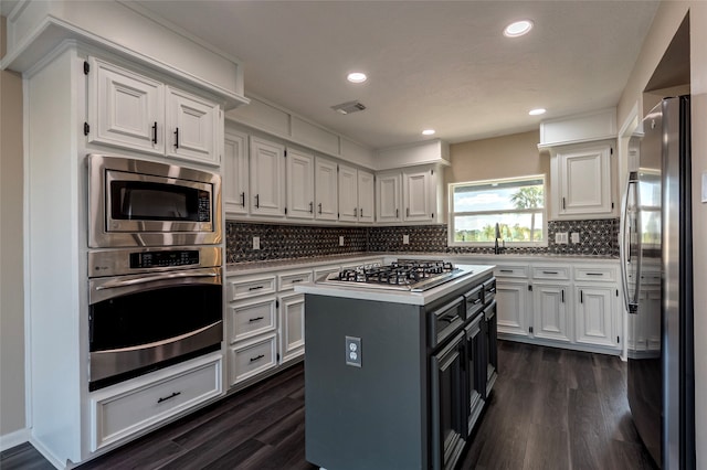 kitchen featuring a kitchen island, stainless steel appliances, tasteful backsplash, dark hardwood / wood-style flooring, and white cabinetry