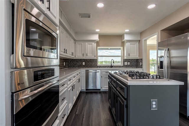 kitchen featuring white cabinets, appliances with stainless steel finishes, dark wood-type flooring, and a kitchen island