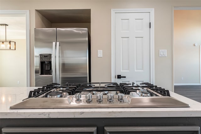 details featuring appliances with stainless steel finishes, light stone counters, and hardwood / wood-style floors