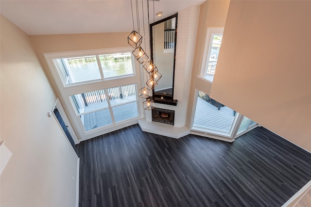 unfurnished living room with a brick fireplace, dark wood-type flooring, and a high ceiling