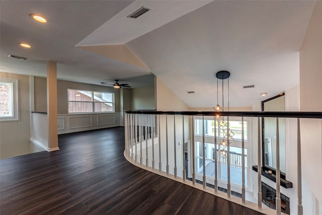 corridor featuring plenty of natural light, dark hardwood / wood-style floors, and vaulted ceiling