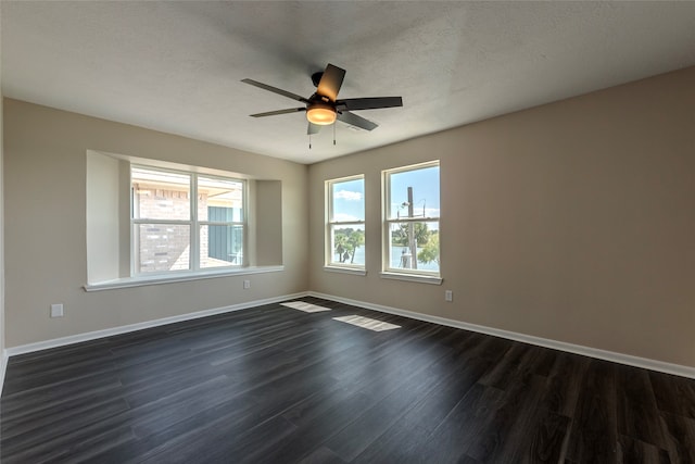 spare room featuring a textured ceiling, dark hardwood / wood-style floors, a wealth of natural light, and ceiling fan