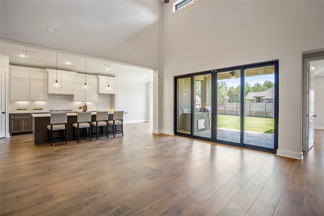 kitchen featuring white cabinets, hanging light fixtures, high vaulted ceiling, hardwood / wood-style flooring, and a center island