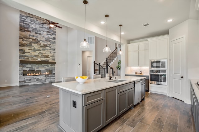 kitchen with a center island with sink, dark wood-type flooring, hanging light fixtures, and stainless steel appliances