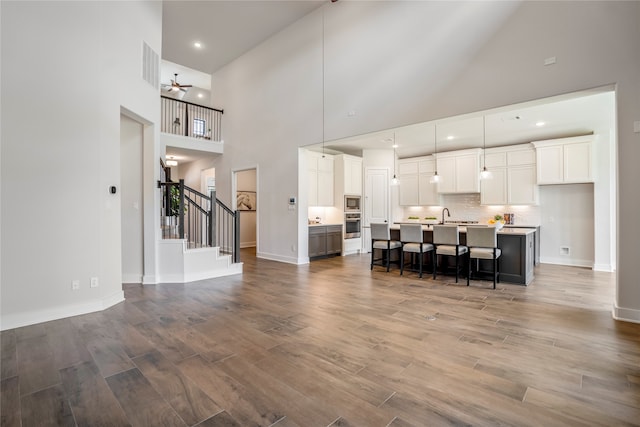 kitchen featuring a center island with sink, high vaulted ceiling, decorative light fixtures, and hardwood / wood-style floors