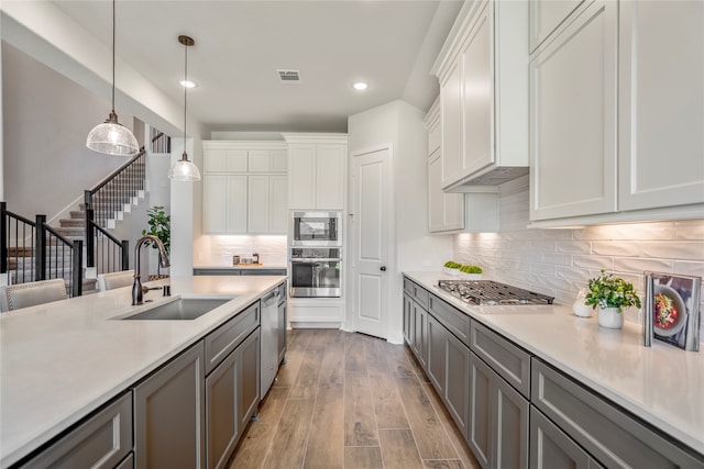 kitchen featuring stainless steel appliances, light hardwood / wood-style floors, gray cabinets, and sink