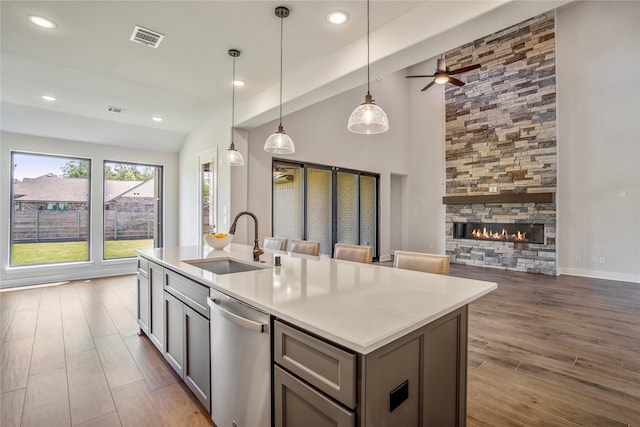 kitchen featuring gray cabinetry, pendant lighting, sink, dishwasher, and a fireplace