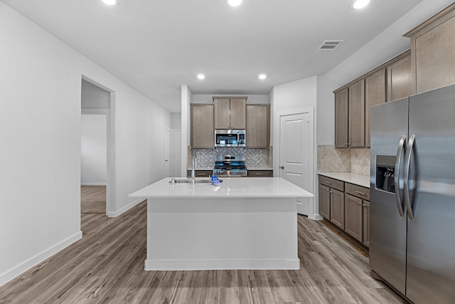 kitchen featuring a kitchen island with sink, appliances with stainless steel finishes, light hardwood / wood-style floors, and sink