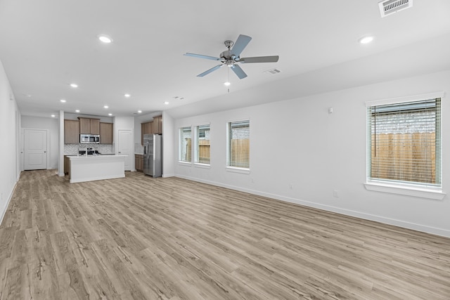 unfurnished living room featuring ceiling fan, a healthy amount of sunlight, and light hardwood / wood-style flooring