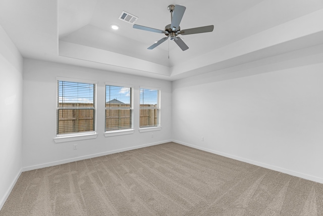 carpeted spare room featuring ceiling fan and a raised ceiling