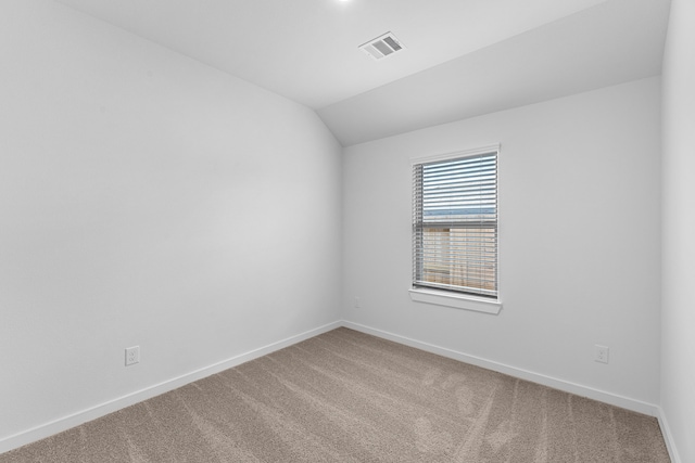 carpeted empty room featuring lofted ceiling