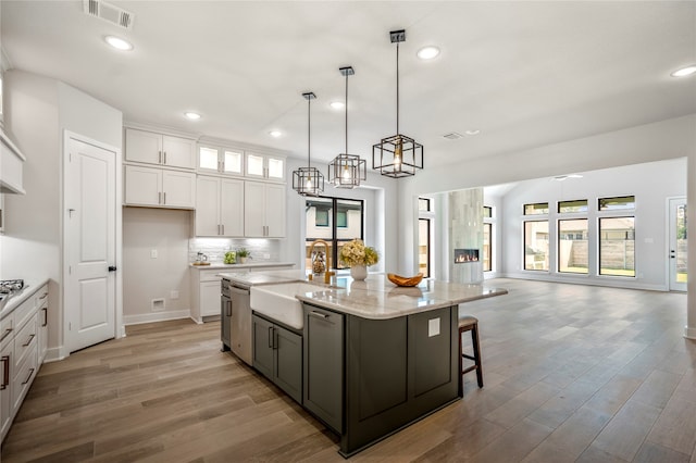 kitchen featuring a center island with sink, plenty of natural light, white cabinetry, and sink