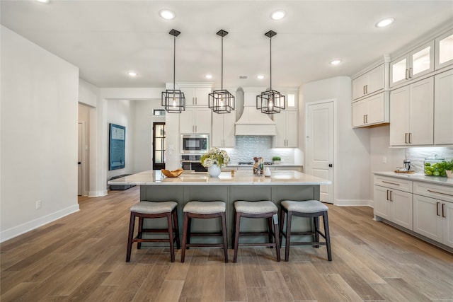 kitchen with hanging light fixtures, light wood-type flooring, appliances with stainless steel finishes, and a center island