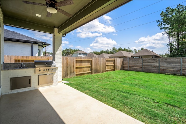 view of yard featuring exterior kitchen, ceiling fan, sink, and a patio area