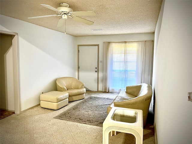 living area with ceiling fan, a textured ceiling, and carpet flooring