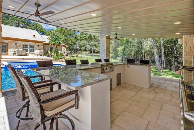 view of patio featuring ceiling fan, grilling area, and exterior kitchen