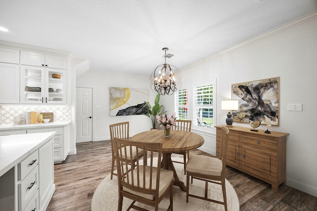 dining area featuring an inviting chandelier, dark hardwood / wood-style floors, ornamental molding, and a textured ceiling