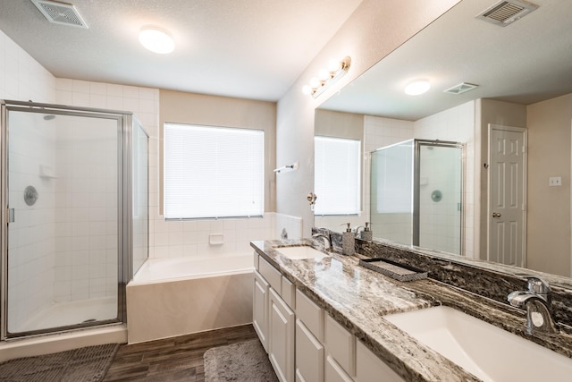 bathroom with wood-type flooring, separate shower and tub, vanity, and a textured ceiling