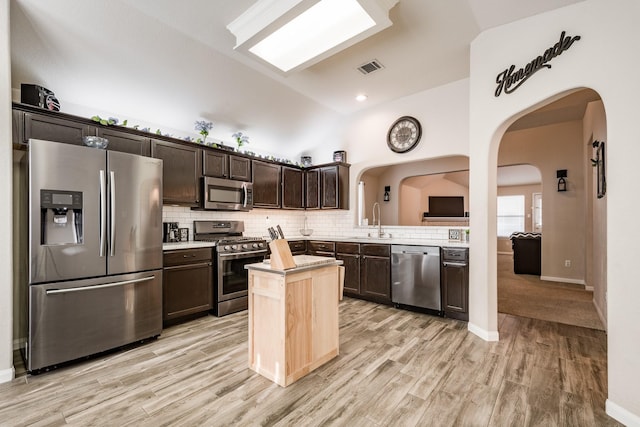 kitchen featuring appliances with stainless steel finishes, sink, dark brown cabinets, and light wood-type flooring