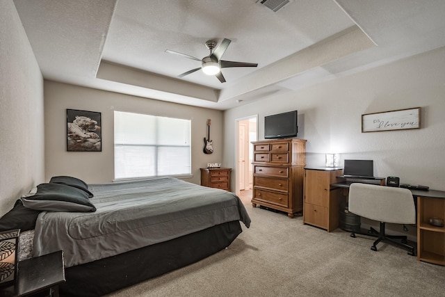 carpeted bedroom featuring ceiling fan and a tray ceiling