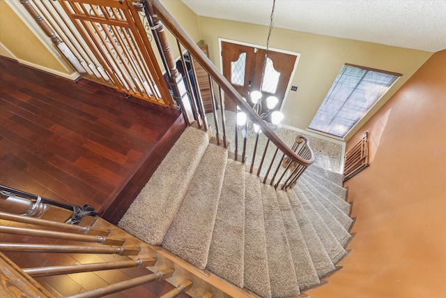 stairway featuring vaulted ceiling, french doors, hardwood / wood-style floors, and a textured ceiling