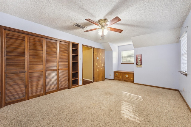 unfurnished bedroom featuring ceiling fan, a textured ceiling, a closet, and carpet