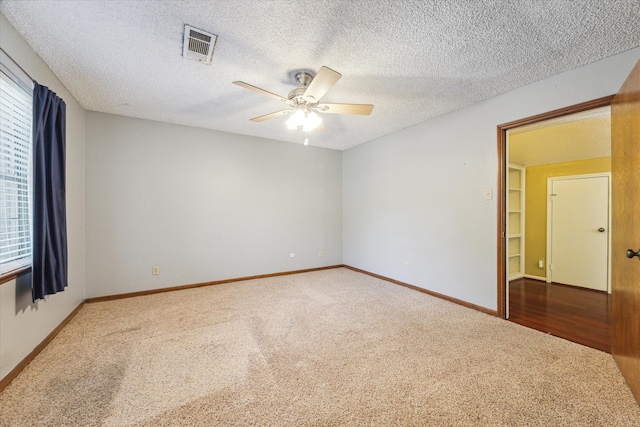 carpeted spare room with ceiling fan and a textured ceiling