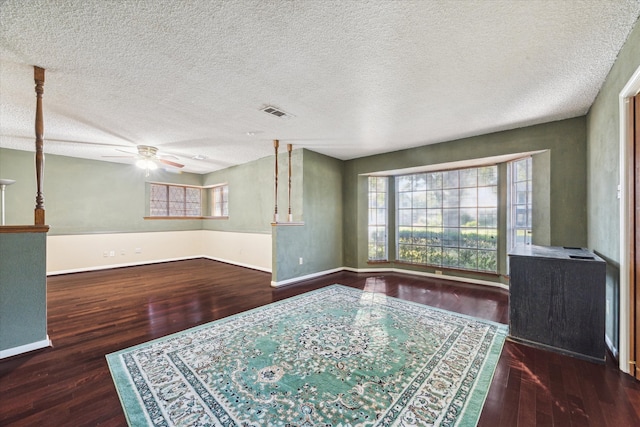 interior space with a textured ceiling, ceiling fan, and dark hardwood / wood-style flooring