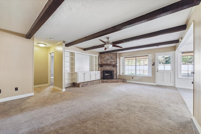 unfurnished living room featuring light colored carpet, beamed ceiling, a textured ceiling, and a fireplace