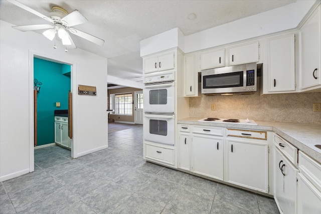 kitchen featuring ceiling fan, white cabinets, light tile patterned flooring, tasteful backsplash, and white appliances