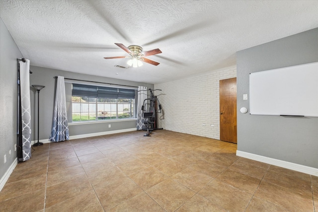 interior space featuring brick wall, a textured ceiling, tile patterned floors, and ceiling fan