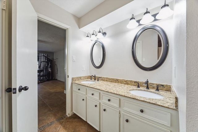 bathroom with tile patterned flooring, vanity, and a textured ceiling