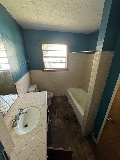 bathroom featuring vanity, a textured ceiling, a shower, tile walls, and toilet