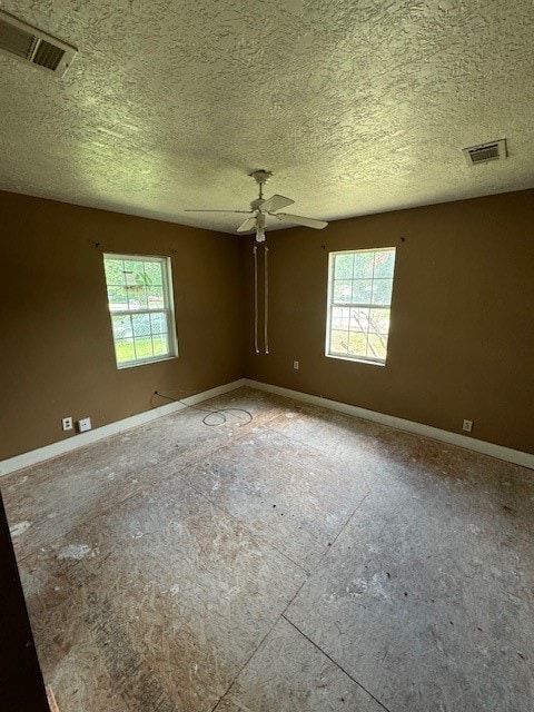 empty room featuring ceiling fan, a textured ceiling, and plenty of natural light