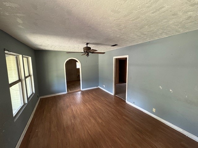 unfurnished room with ceiling fan, dark wood-type flooring, and a textured ceiling