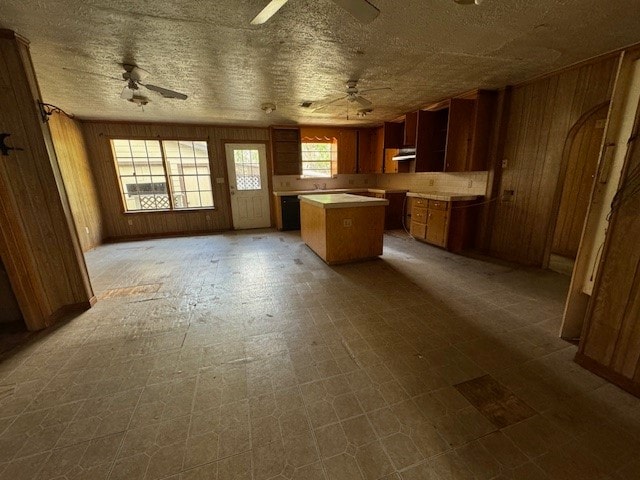 kitchen featuring ceiling fan, wood walls, and a center island