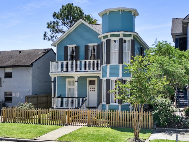 view of front of property featuring covered porch, a balcony, and a front yard