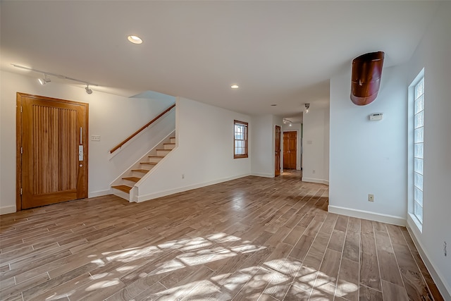 unfurnished living room featuring track lighting and light hardwood / wood-style flooring