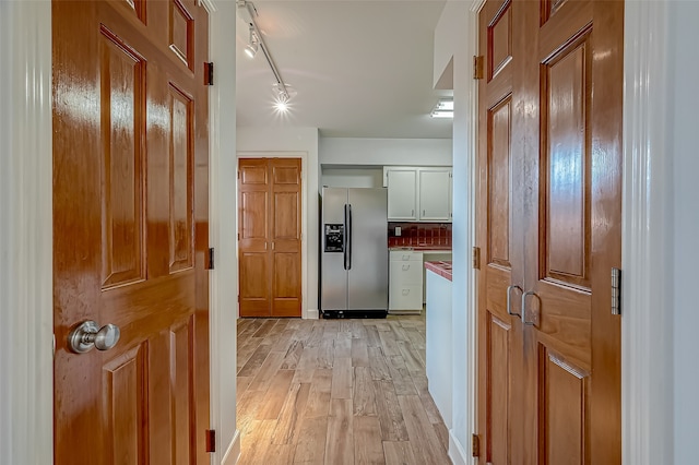 hallway featuring rail lighting and light hardwood / wood-style floors