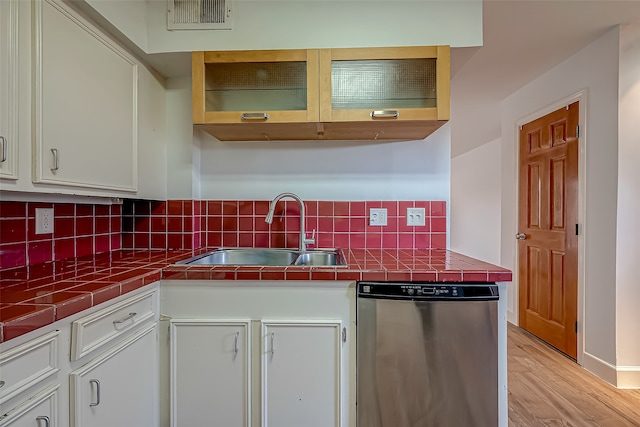 kitchen featuring dishwasher, backsplash, sink, light wood-type flooring, and white cabinets