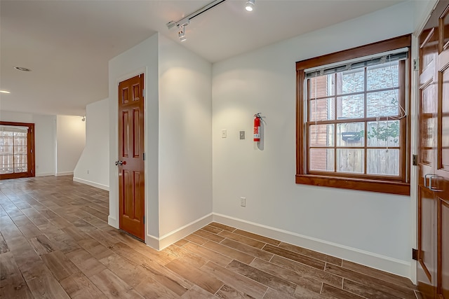 unfurnished room featuring rail lighting and wood-type flooring