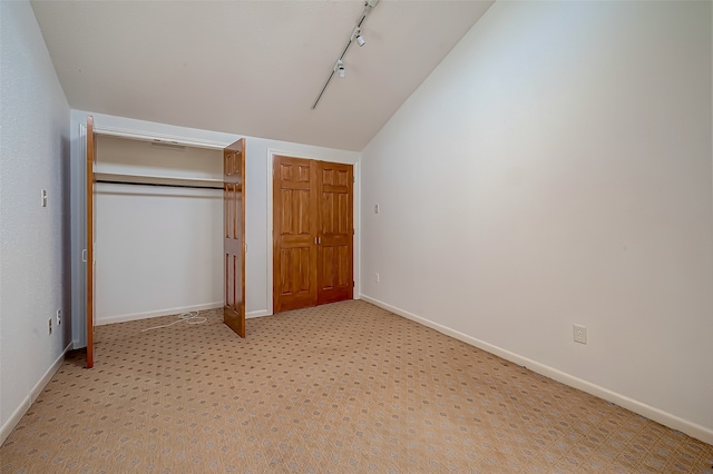 unfurnished bedroom with lofted ceiling, a closet, and light colored carpet