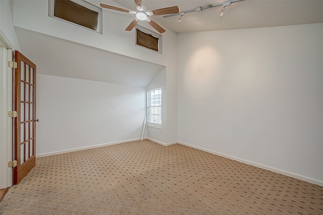 spare room with ceiling fan, light carpet, track lighting, and lofted ceiling